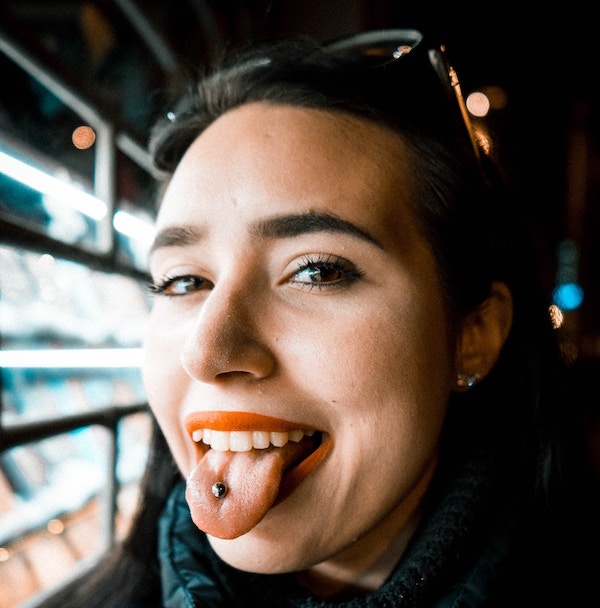 Woman sticks out tongue to show tongue jewelry.
