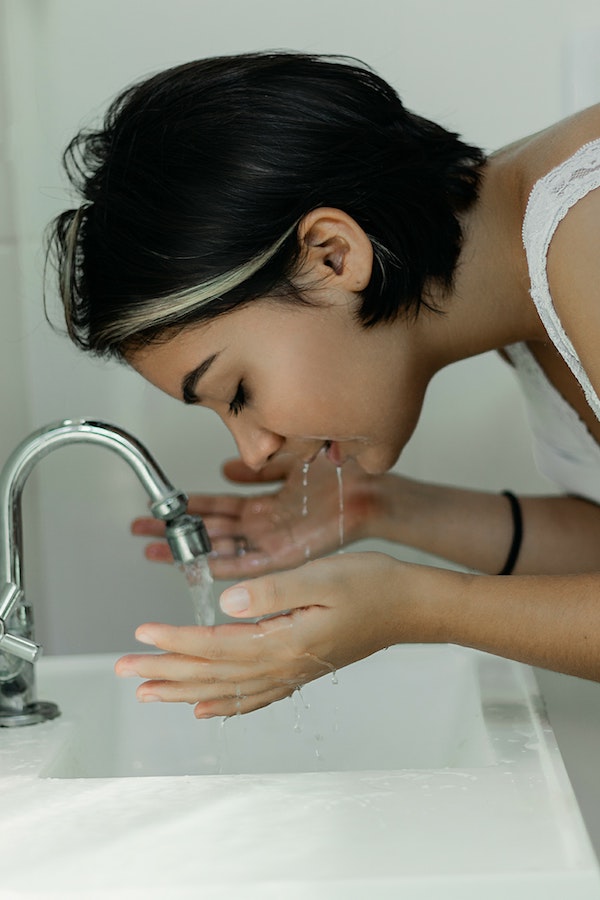 a woman washes her face in a sink