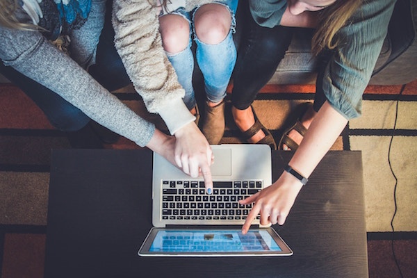 Three girls look at a computer